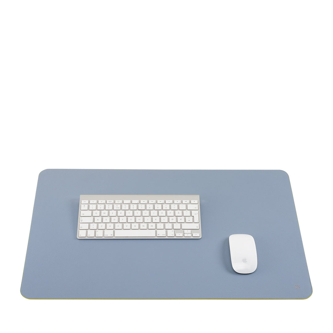 Minimalist desk setup with blue mouse pad, white keyboard, and wireless mouse