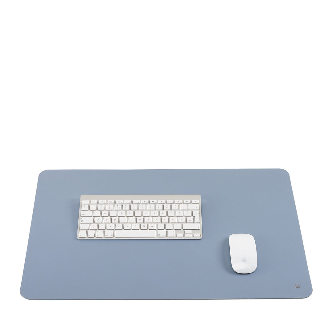 Minimalist workspace with white keyboard and mouse on blue mat
