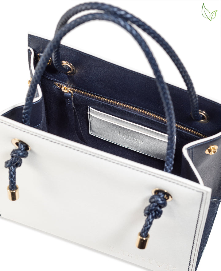White and navy blue luxury handbag with gold accents and rope handles