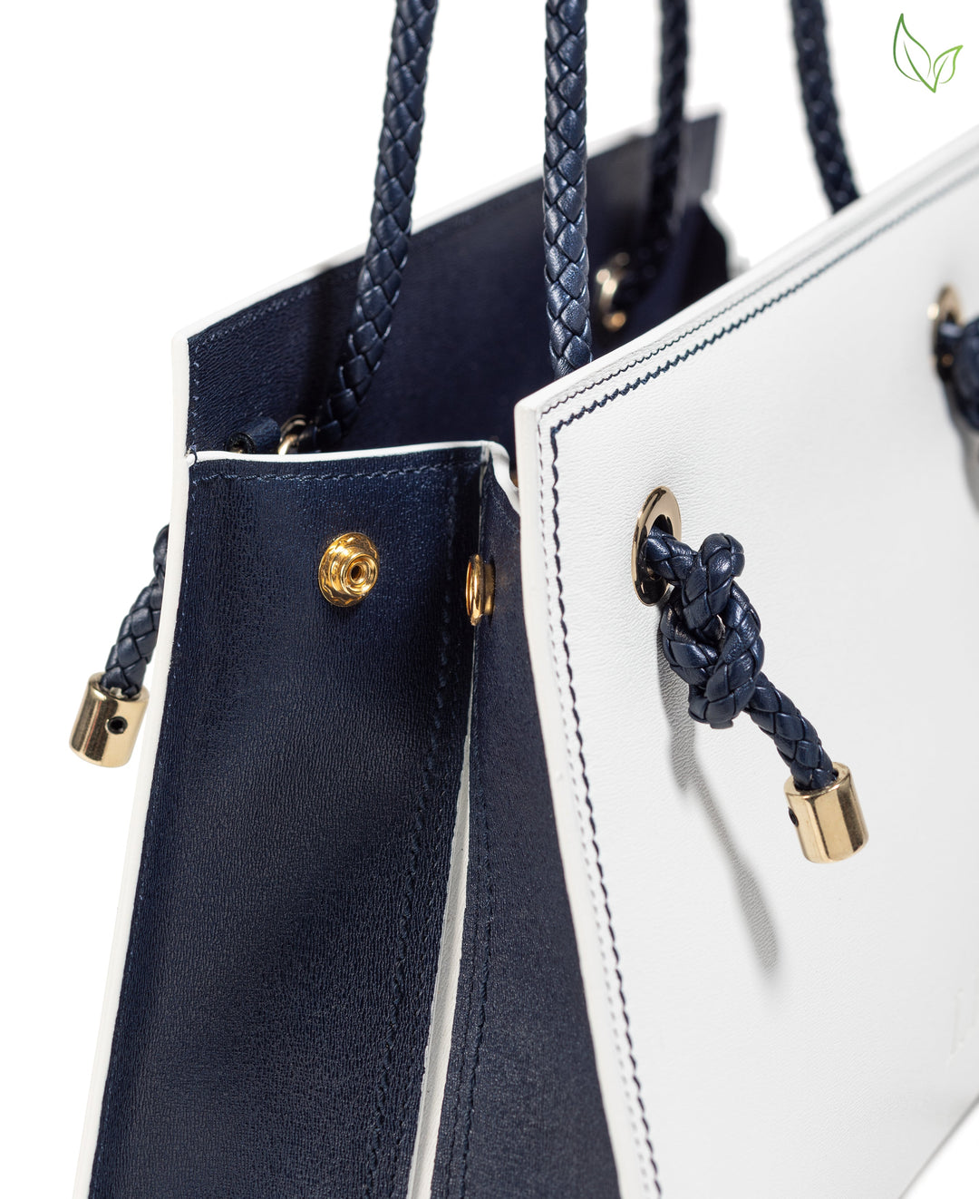 Close-up of a stylish white and navy blue handbag with braided handles and gold accents