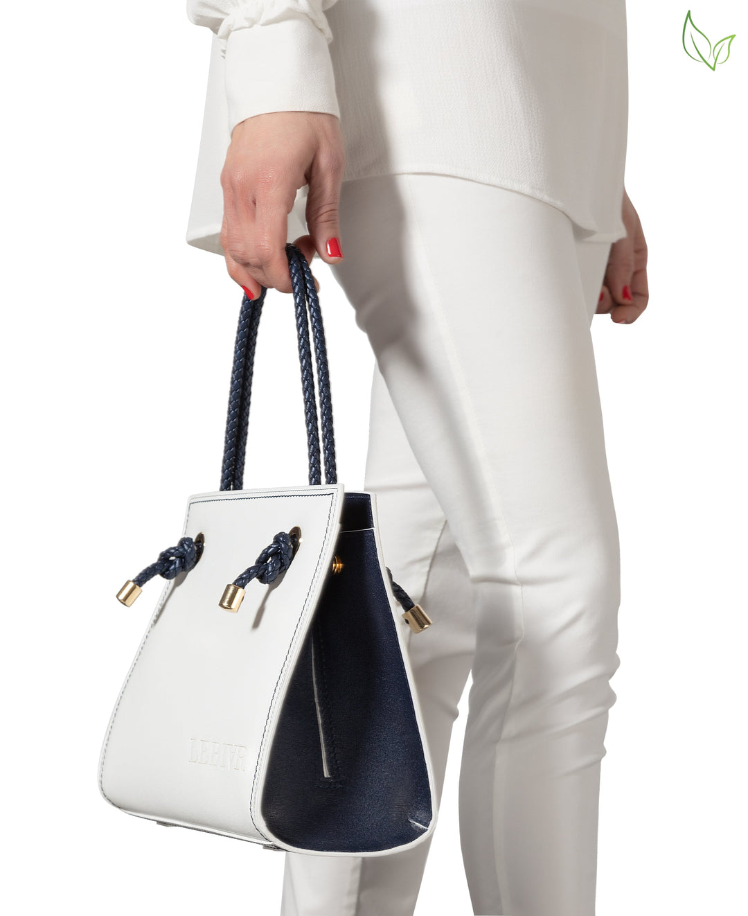 Woman holding a stylish white handbag with blue accents while wearing white outfit