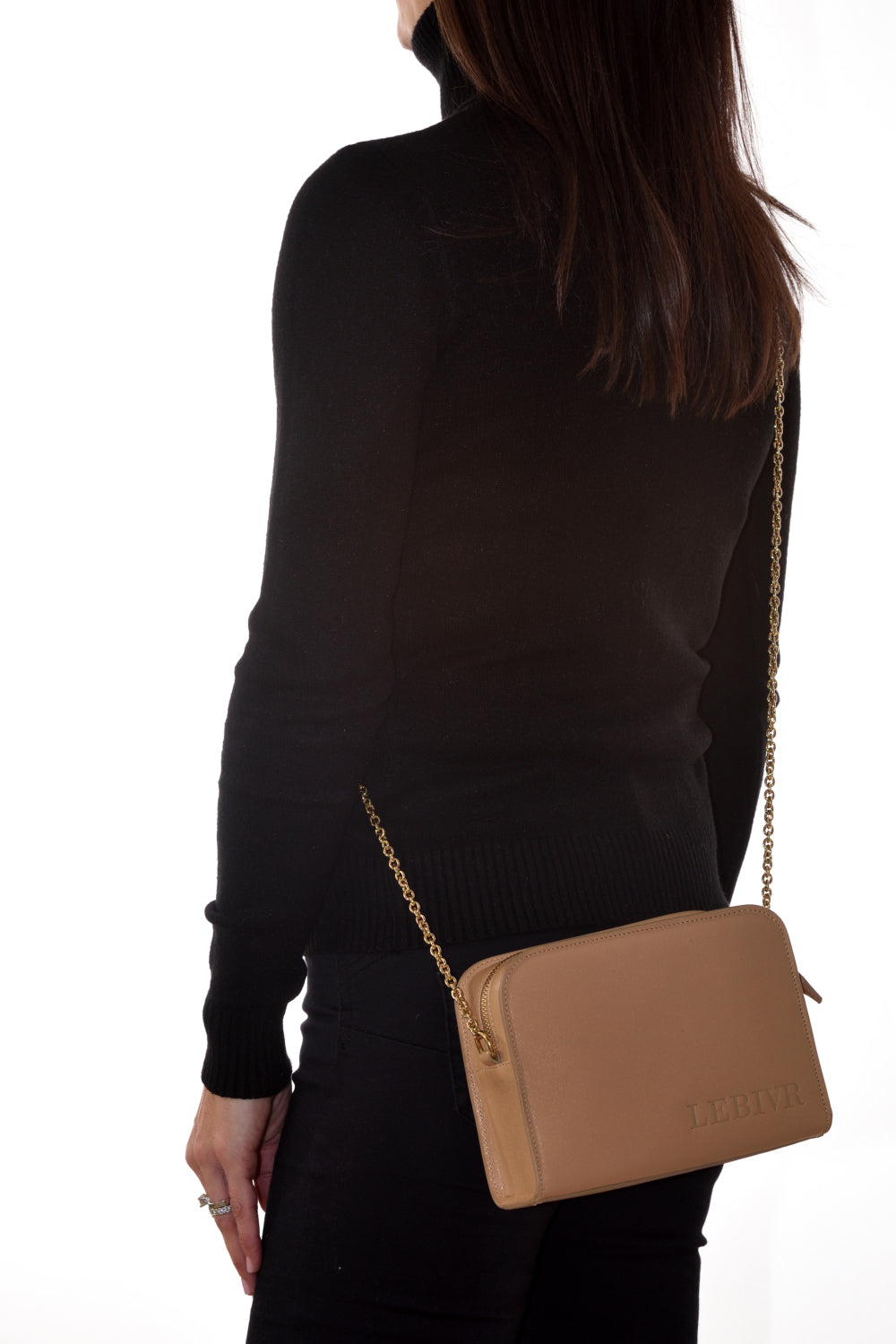 Woman with brown leather crossbody handbag and gold chain strap wearing black sweater