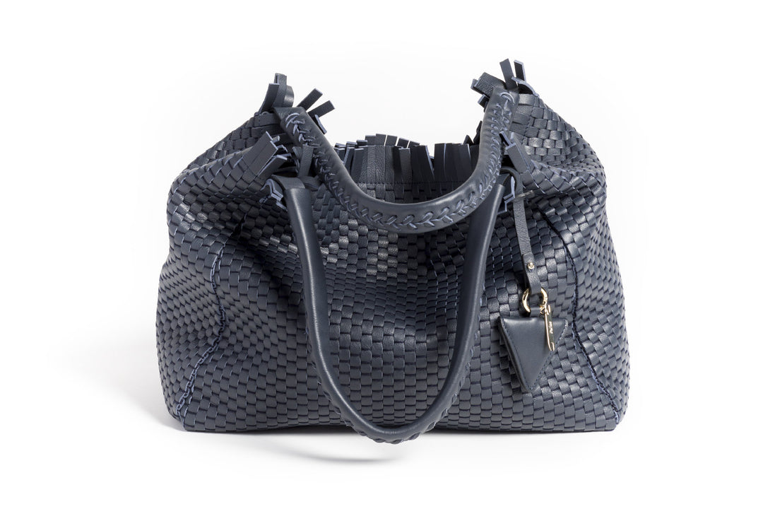 Elegant navy blue woven handbag with leather handles and a decorative pendant.