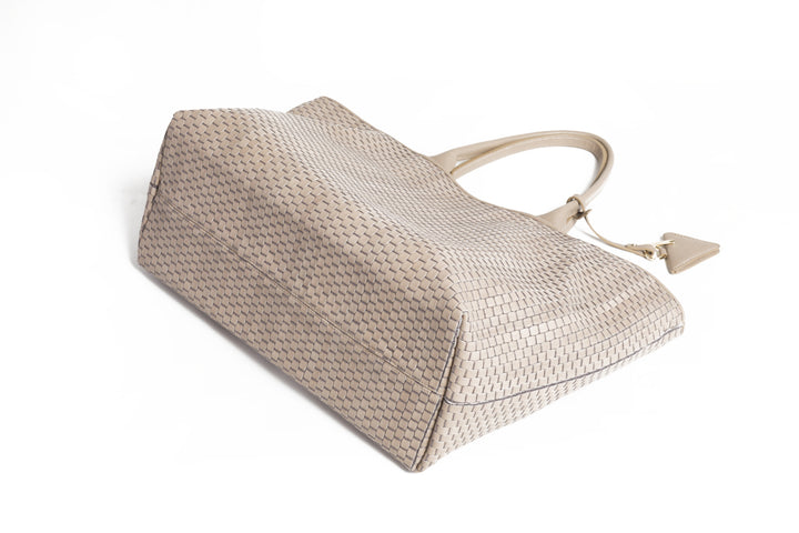 Elegant beige woven tote bag on white background.