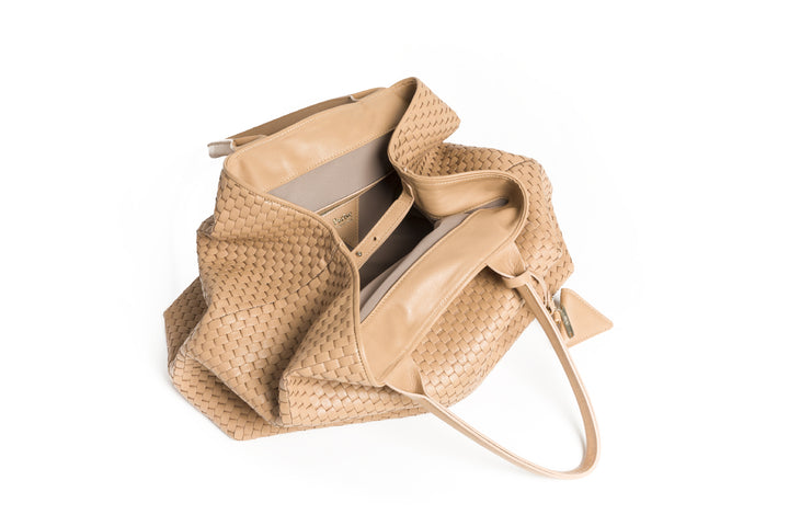 Handcrafted beige woven leather tote bag with dual handles and a triangular charm.