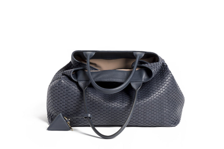 Elegant black woven tote bag with leather straps and decorative tag.