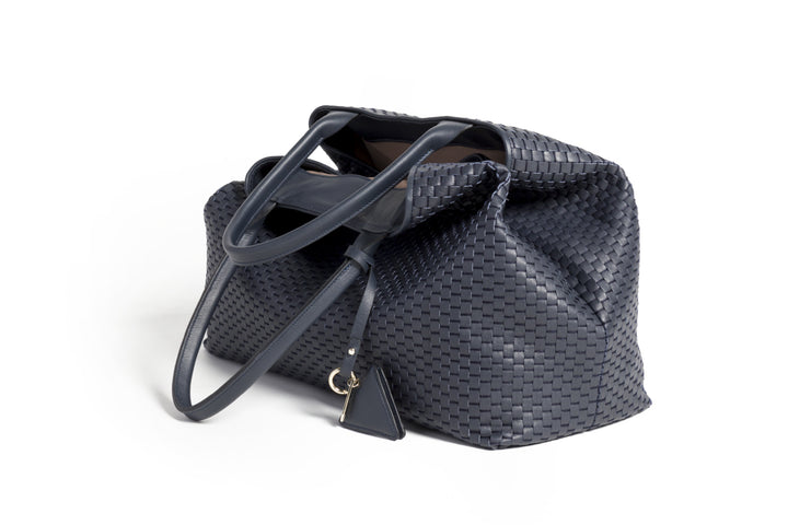 Elegant black woven tote bag with leather straps and decorative tag.