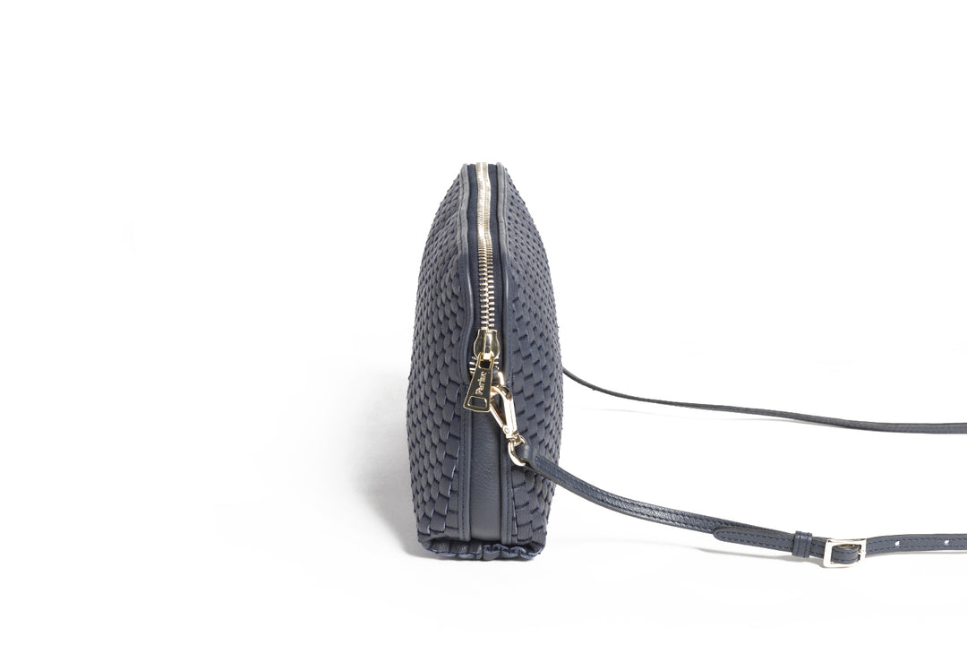 Dark blue woven leather handbag with shoulder strap and zipper closure against white background.