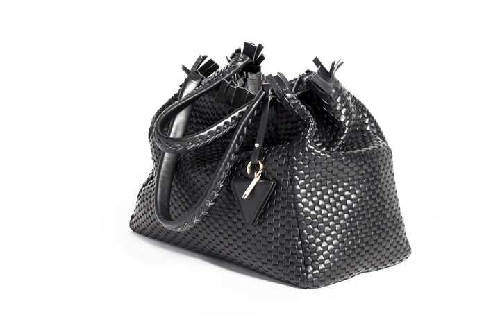 Black woven leather handbag with triangle pendant on white background.