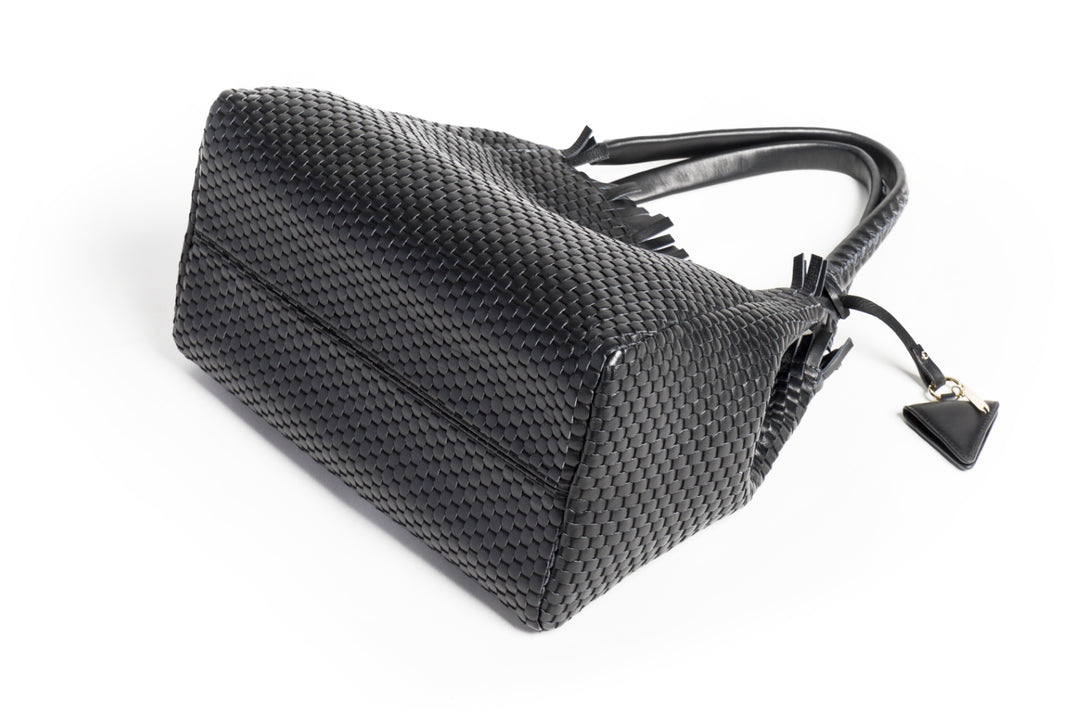 Black woven leather handbag with triangle pendant on white background.