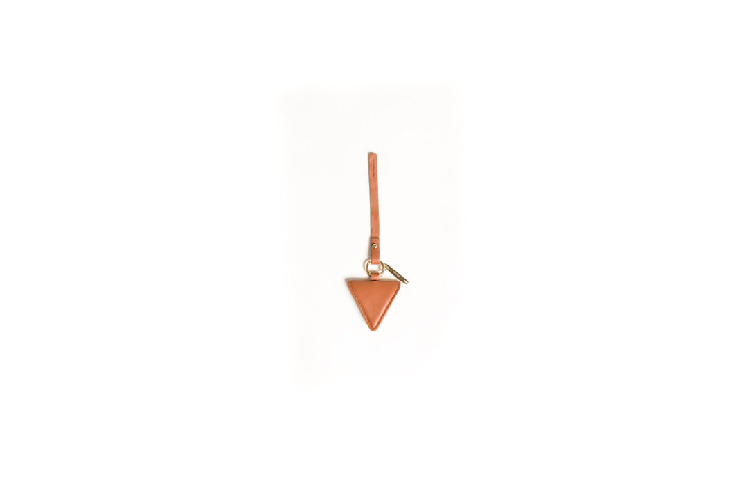 Triangular brown leather keychain with strap and metal ring on white background.