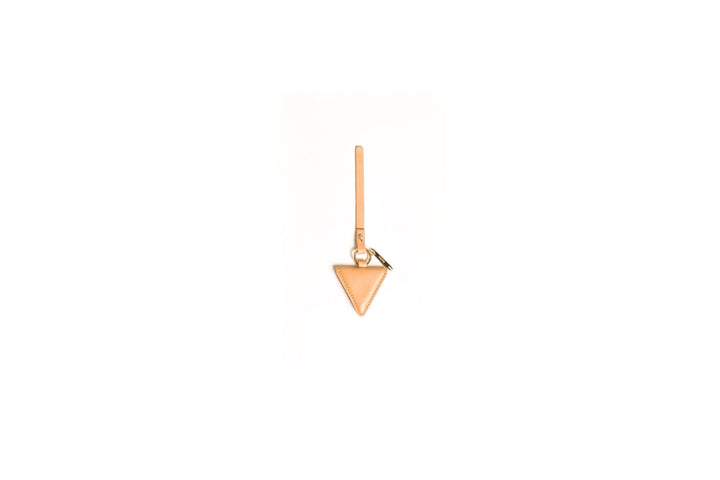 Beige triangular leather keychain against white background