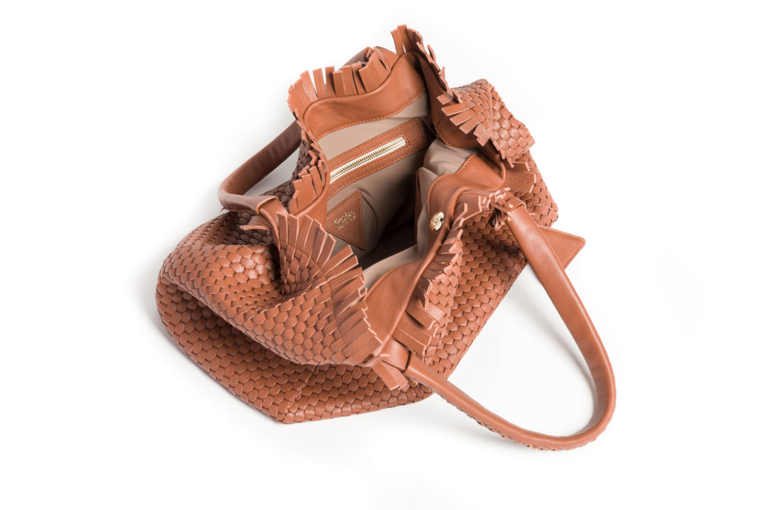 Elegant brown woven leather handbag with double handles and a decorative tassel detail.