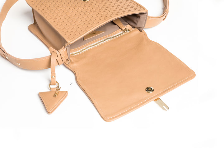 Tan woven leather crossbody bag with gold clasp and adjustable strap on white background.