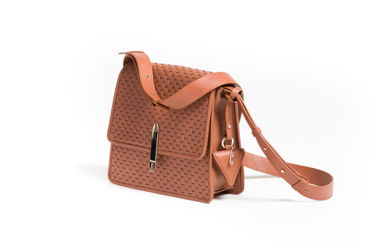 Brown woven leather handbag with adjustable strap on white background.