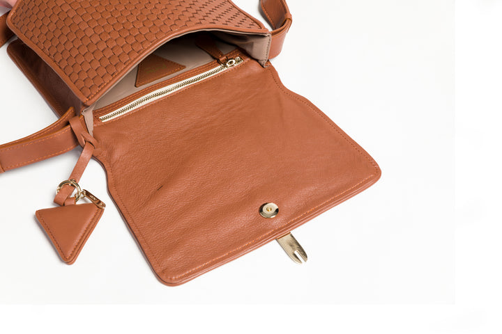 Brown woven leather handbag with adjustable strap on white background.