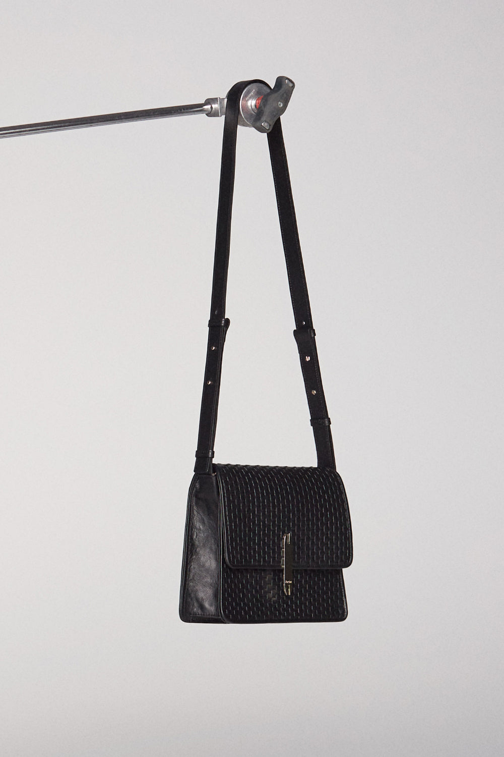 Black woven leather handbag with shoulder strap on white background.