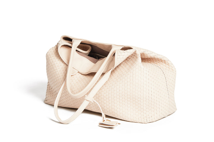 Cream-colored woven leather tote bag with handles and a triangular tag.