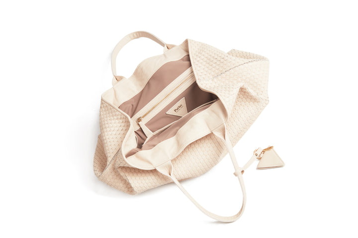 Cream-colored woven leather tote bag with handles and a triangular tag.