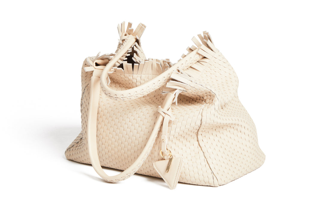 Cream woven handbag with leather straps and tassel detailing.