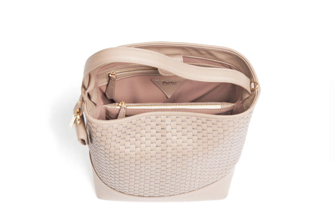 Beige woven leather handbag with adjustable strap on white background.