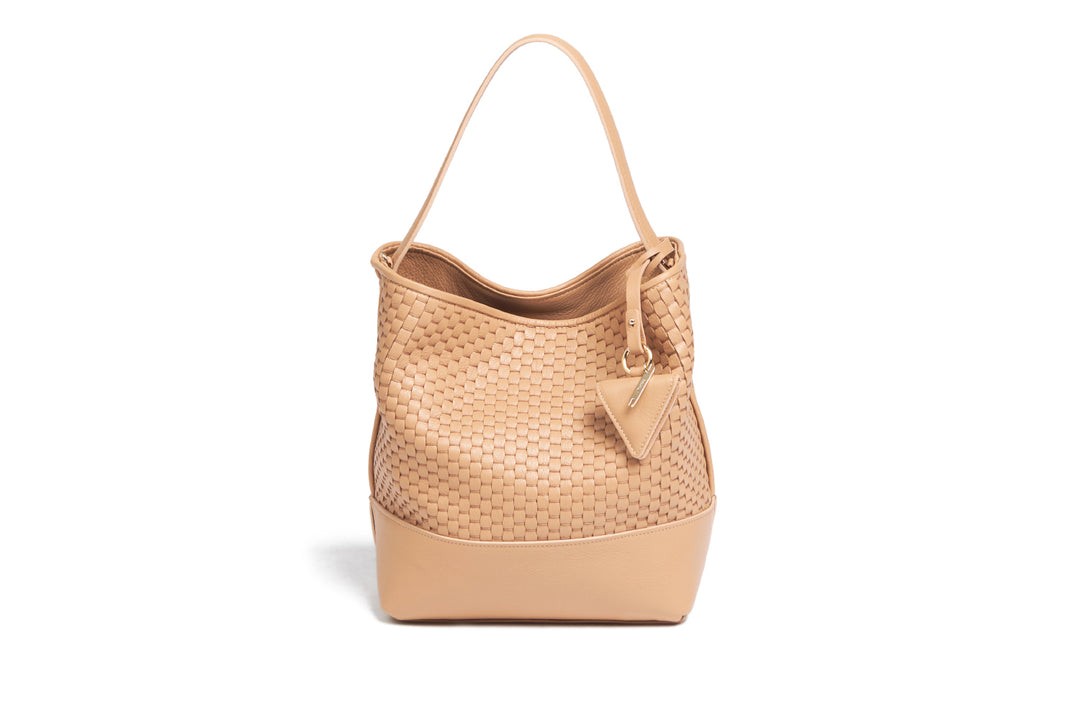 Woven tan leather shoulder bag with adjustable strap and decorative tag.