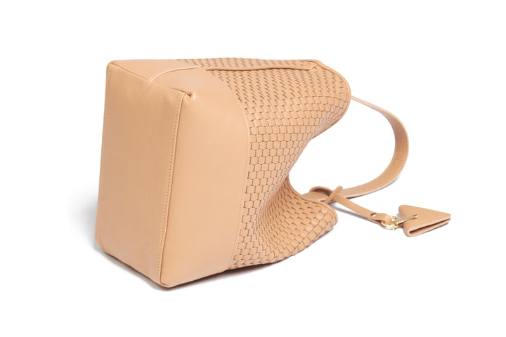 Woven tan leather shoulder bag with adjustable strap and decorative tag.