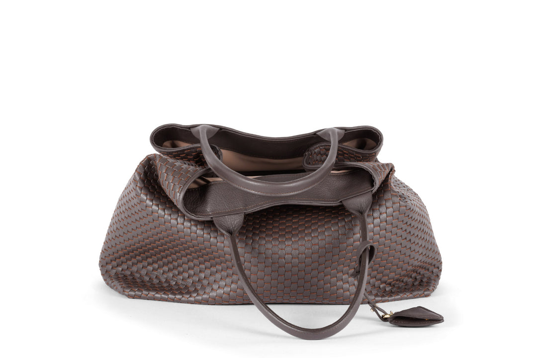 Brown leather woven tote bag with handles and a triangular charm.