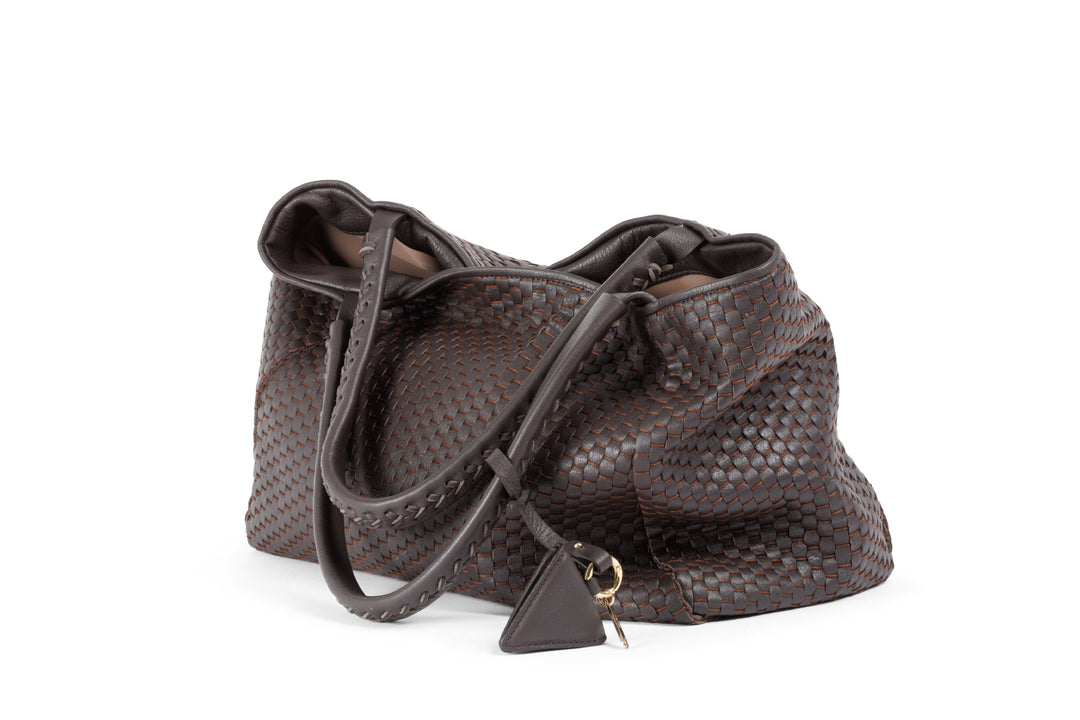 Brown woven leather handbag with a keychain ornament on a white background.