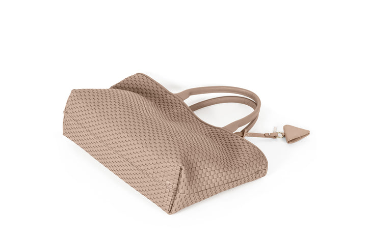 Beige woven tote bag with leather handles and a diamond-shaped keychain accessory.