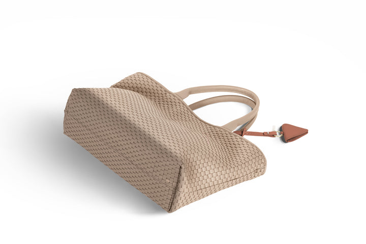 Elegant beige woven tote bag with leather handles and accent tag.