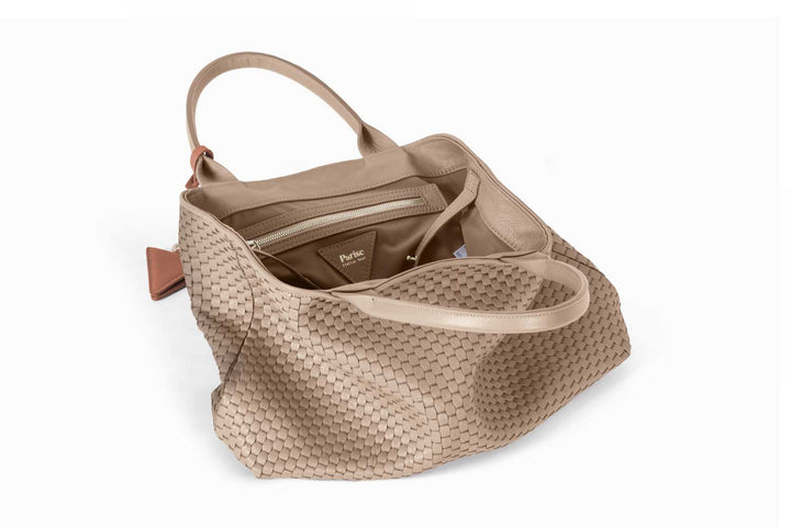 Elegant beige woven tote bag with leather handles and accent tag.