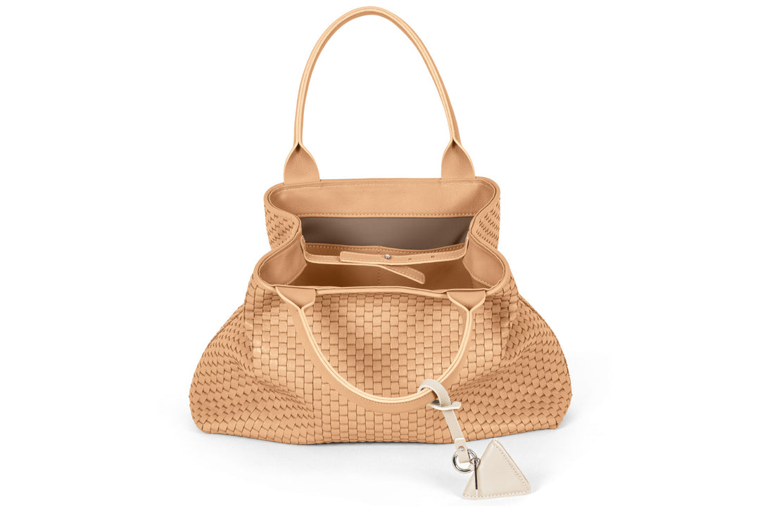 Beige woven handbag with triangular charm on white background.