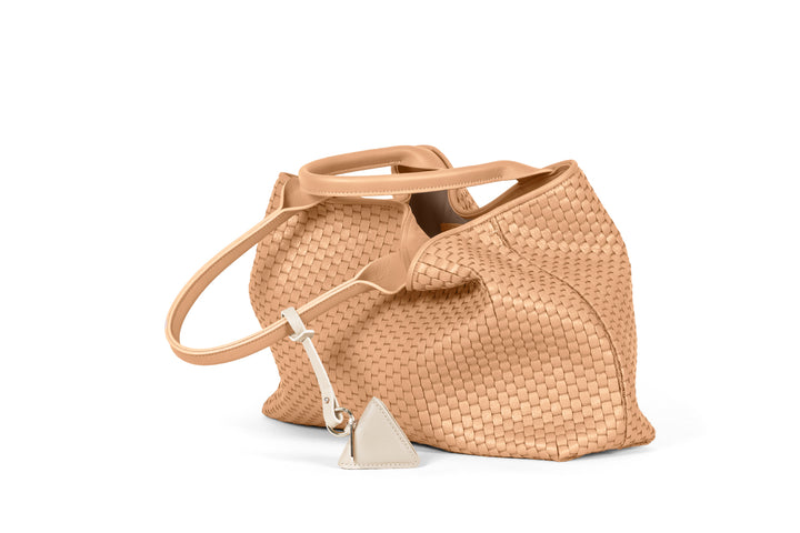 Beige woven handbag with triangular charm on white background.