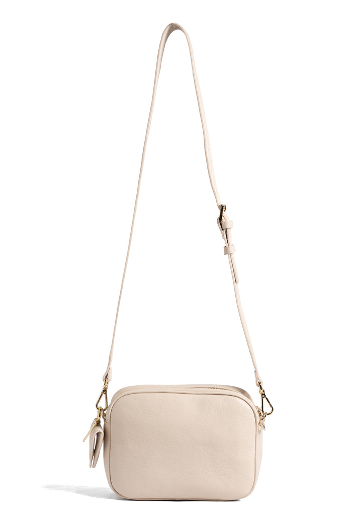 Cream quilted crossbody handbag with adjustable strap.