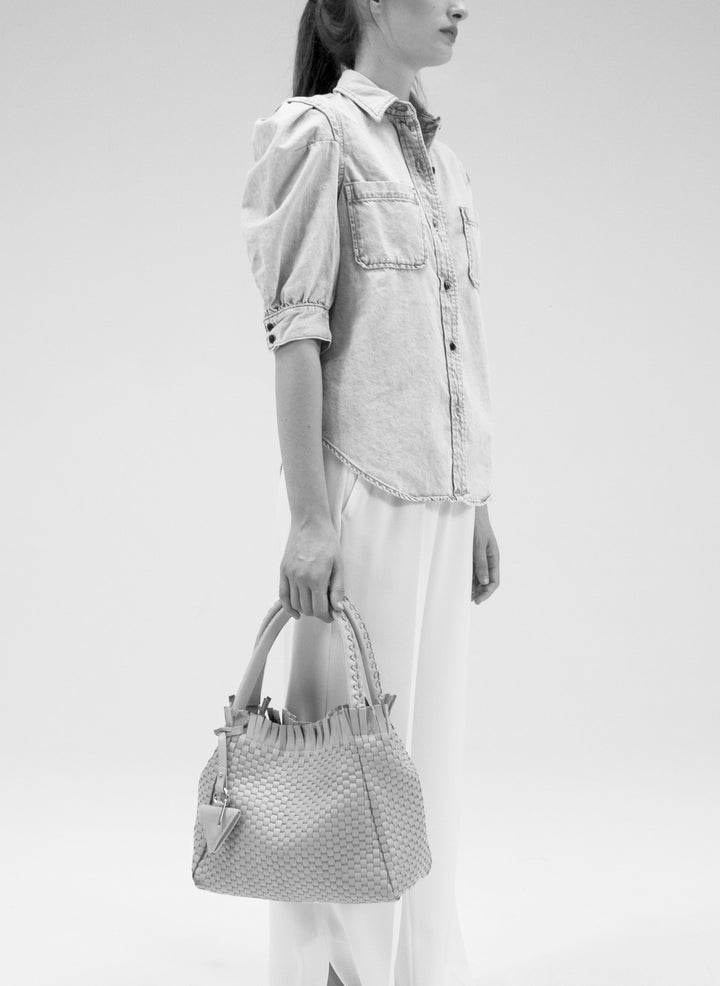 Elegant ivory woven handbag with tassel detail and braided handles.