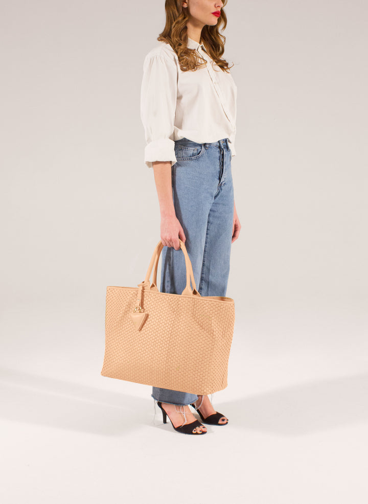 Handcrafted beige woven leather tote bag with dual handles and a triangular charm.