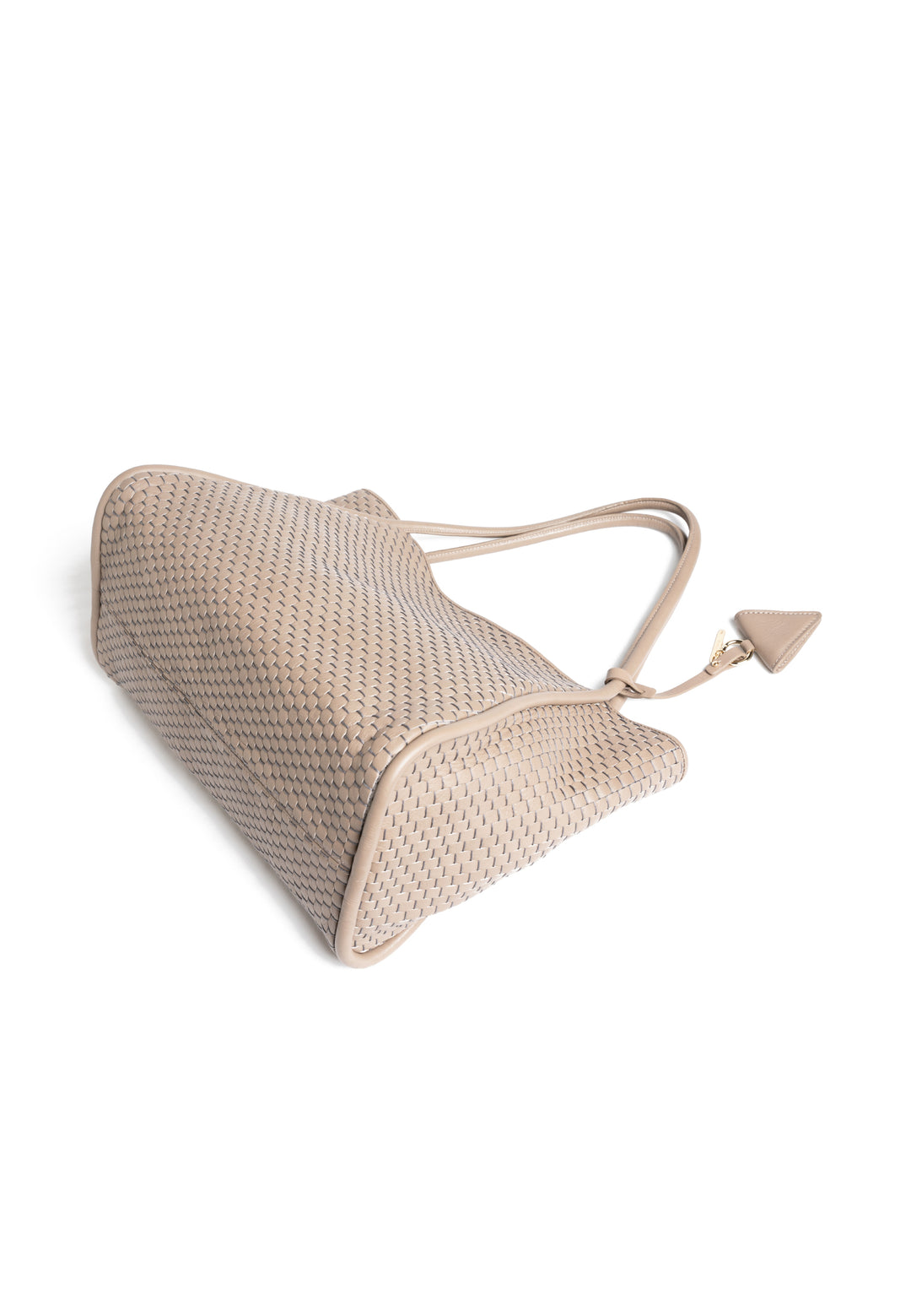 Woven beige handbag with long handles and attached accessory on white background.