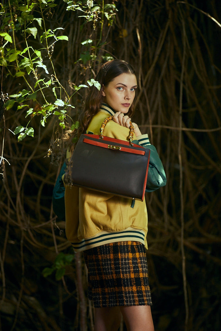 Woman in fashionable outfit holding a luxury handbag in a forest setting