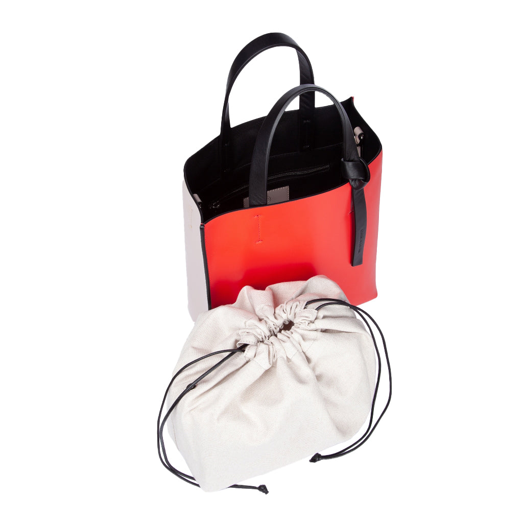 Red and black leather tote bag with a white drawstring pouch