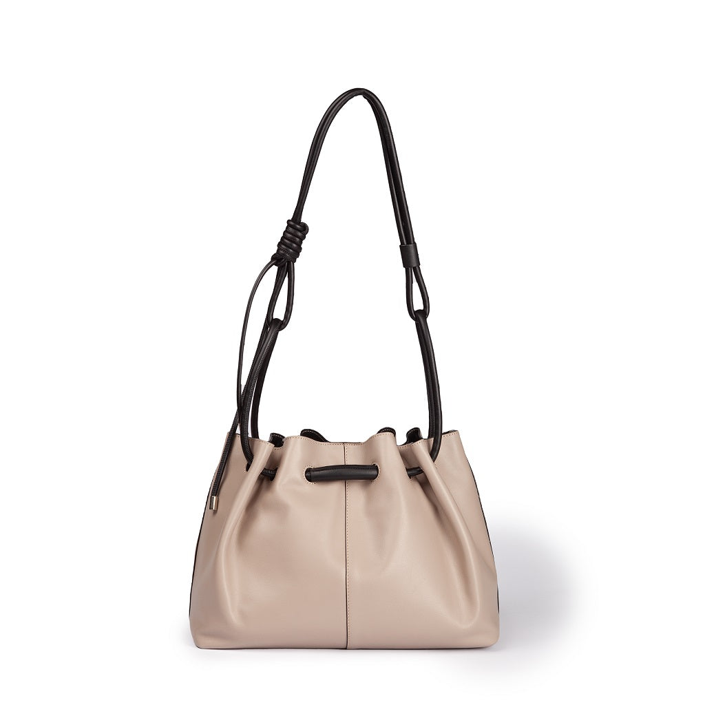 Tan leather bucket bag with black straps on a white background