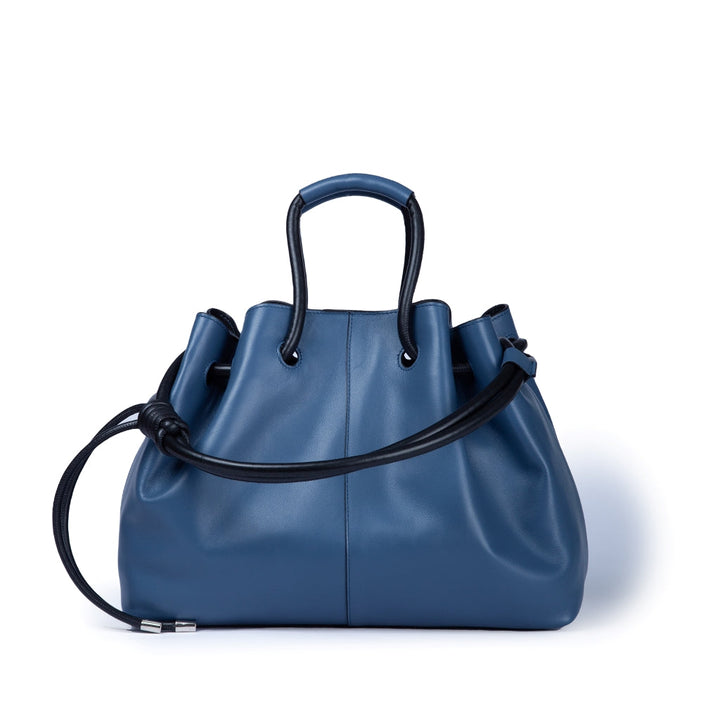 Blue leather handbag with black handles and adjustable strap