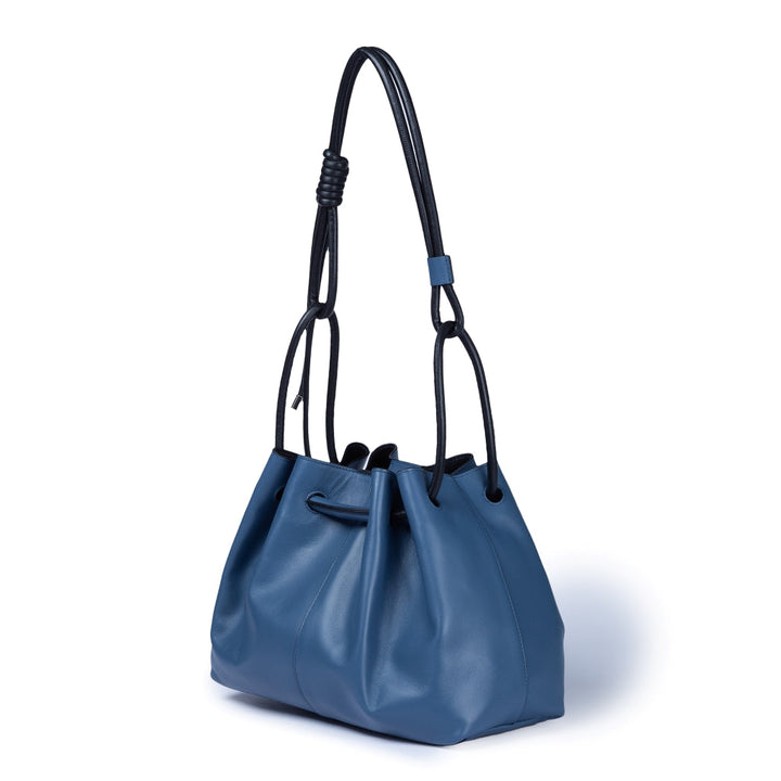 blue leather bucket bag with black handles on white background