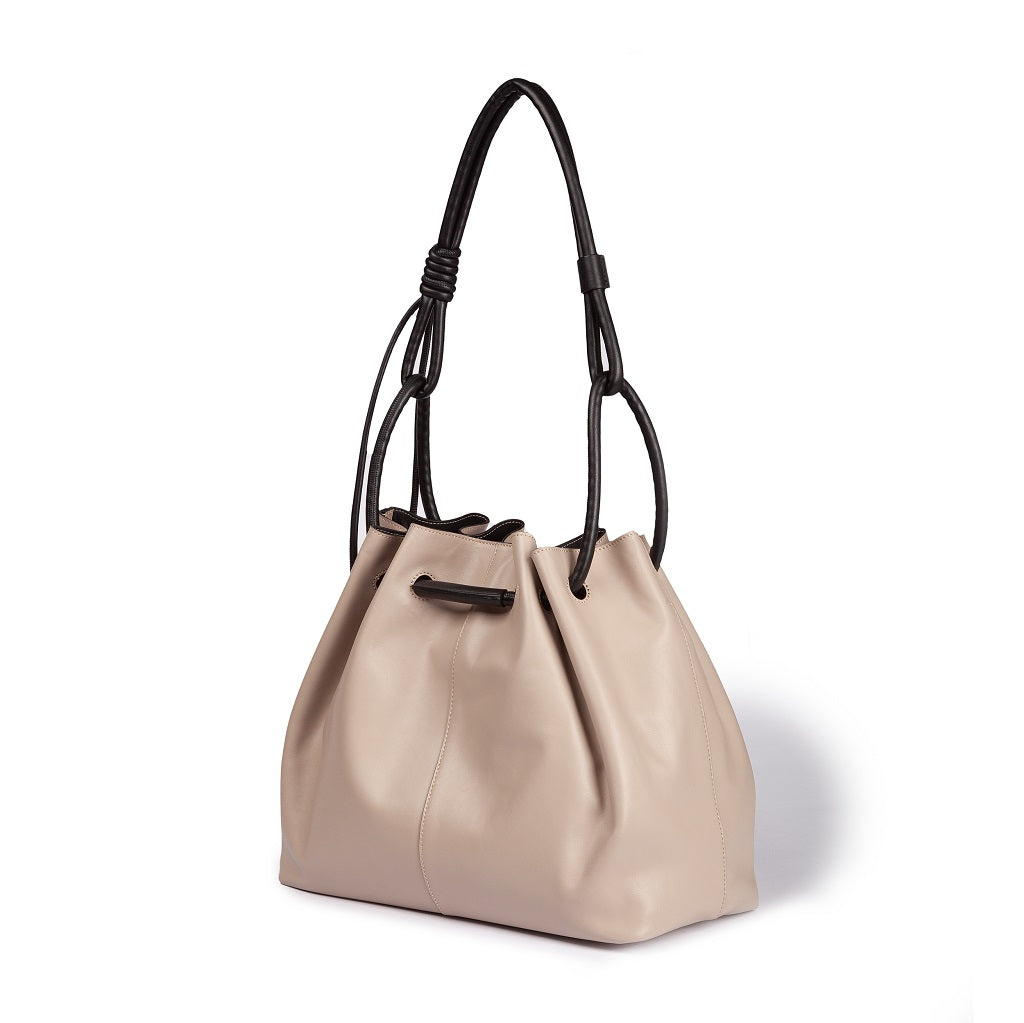 Cream-colored leather handbag with black straps on a white background