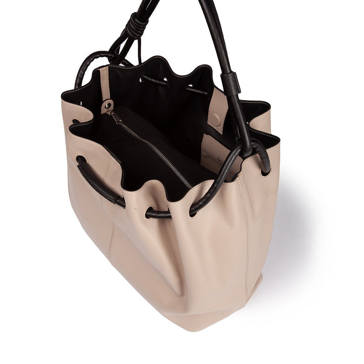 Soft beige leather handbag with black accents and open top view showing interior pockets and drawstring closure