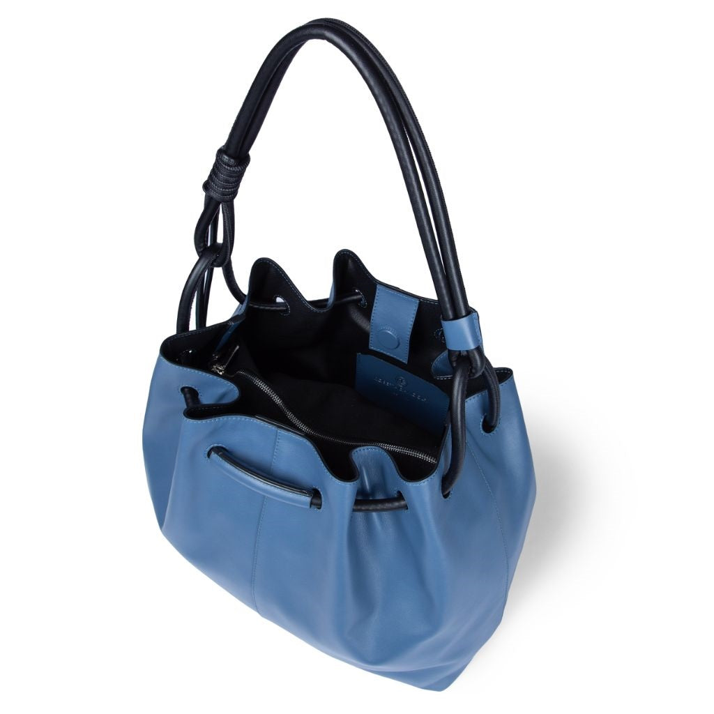 Blue leather bucket bag with black handle on white background