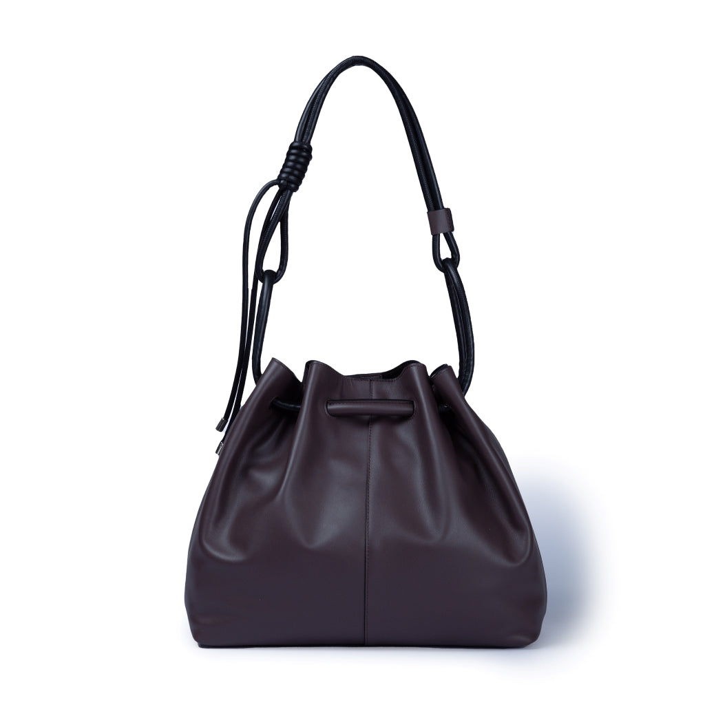 Brown leather bucket bag with black strap and drawstring closure