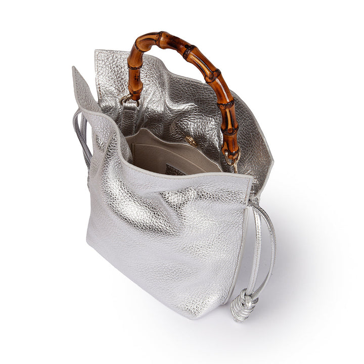 Silver leather handbag with bamboo handle and open interior on white background