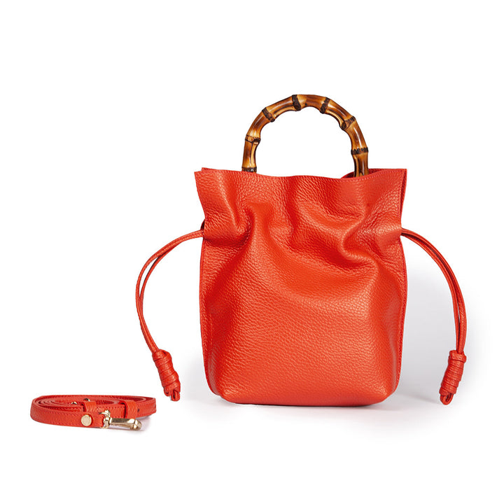 Bright orange leather handbag with bamboo handles and a detachable strap