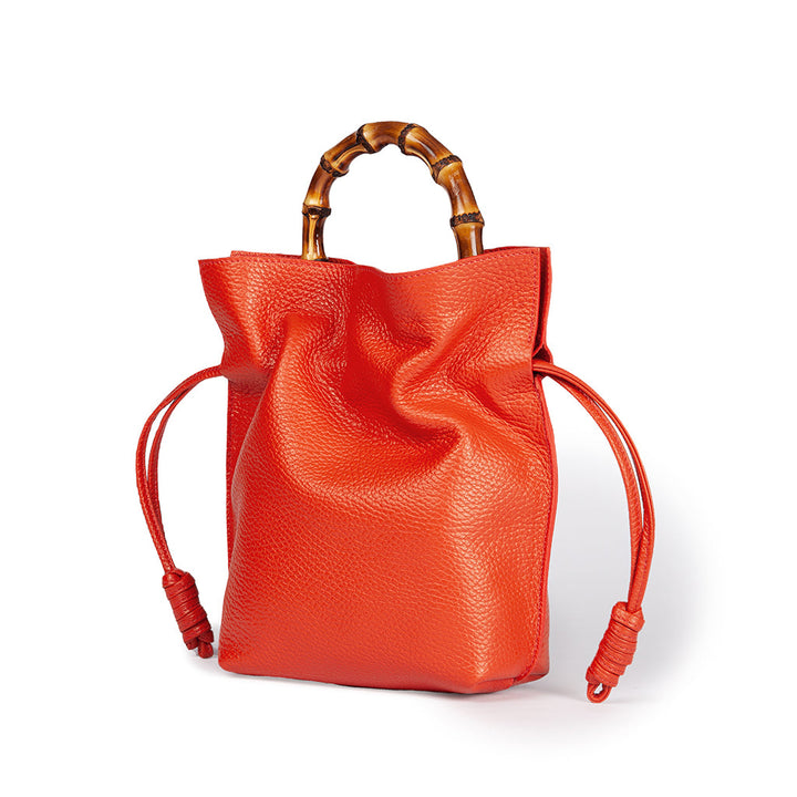 Bright orange leather handbag with bamboo handles and drawstring closure